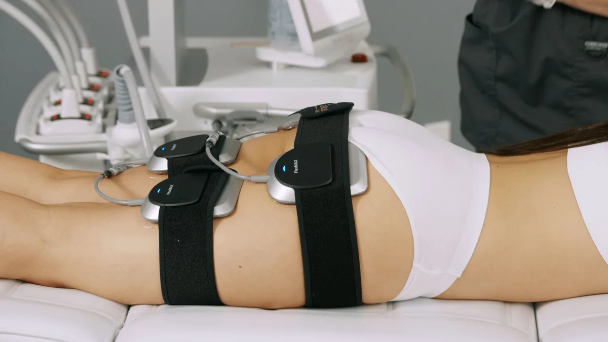 Venus Bliss Max FlexMAX applicators strapped to a client's lower back and hip during a body-contouring session